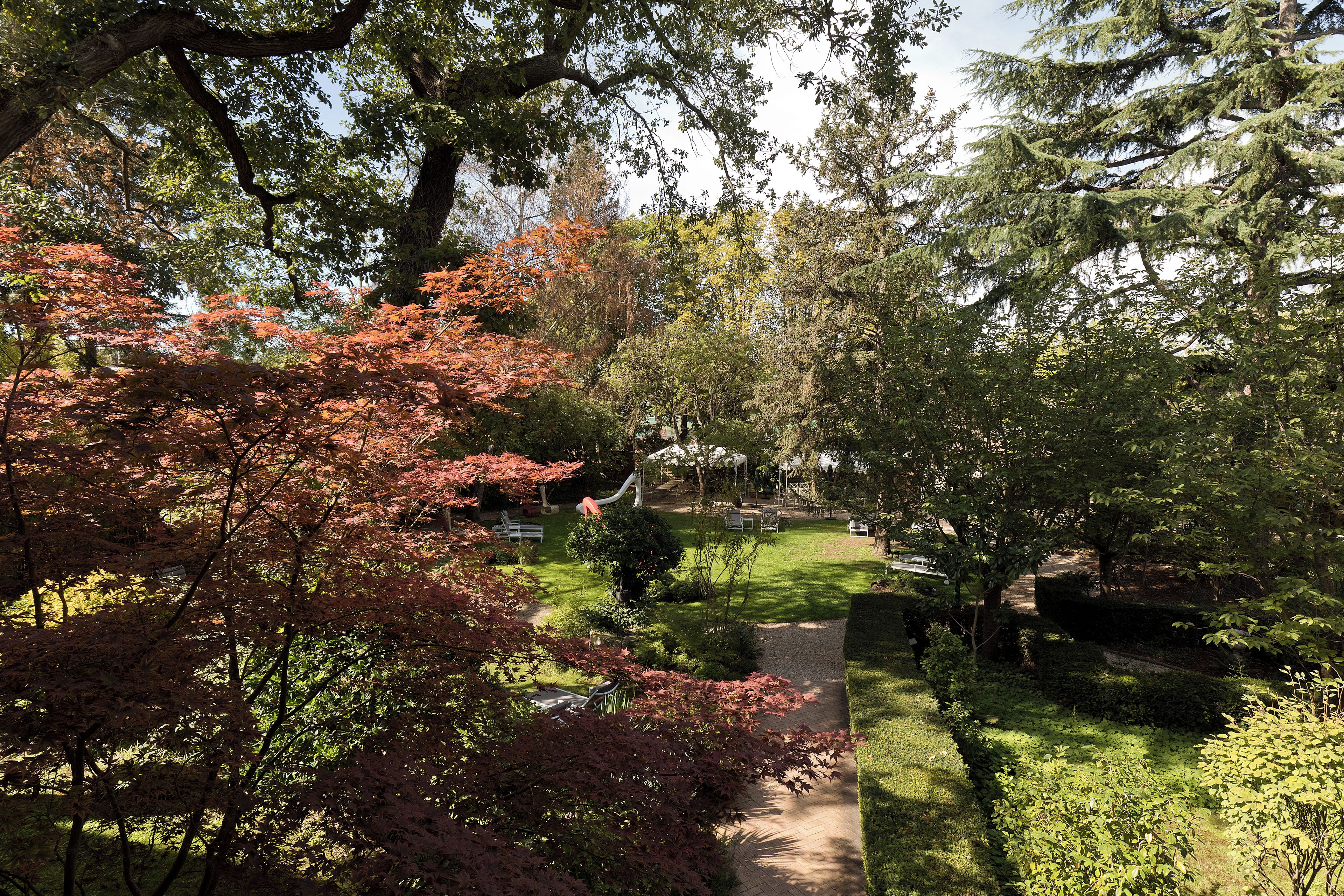 A garden with a pathway, trees, and outdoor seating.