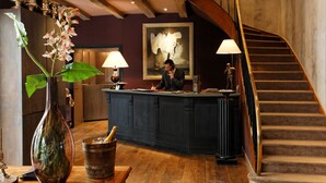 A reception desk with a vase of flowers, a statue, and a painting on the wall. - CAZAUDEHORE Hôtel Restaurant Gastronomique Terrasse et Jardins (Saint-Germain-en-Laye)