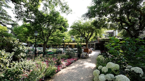 A garden pathway with tables and chairs, surrounded by lush greenery and flowering plants. - CAZAUDEHORE Hôtel Restaurant Gastronomique Terrasse et Jardins (Saint-Germain-en-Laye)