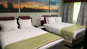 Habitación de hotel con dos camas, una mesita de noche y una ventana con cortinas.