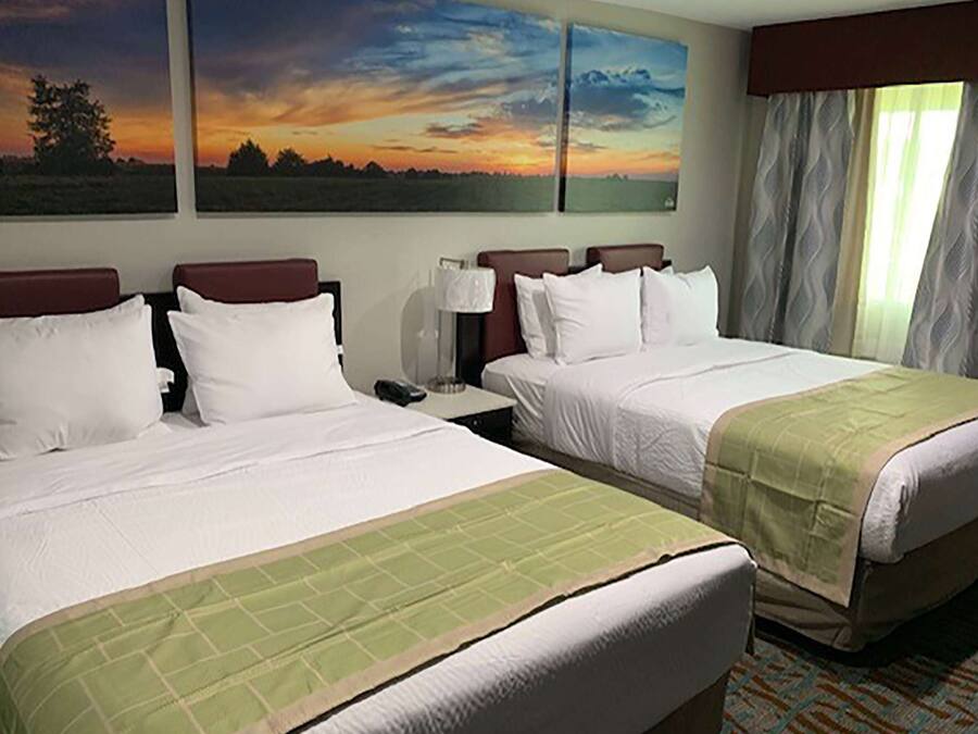 A hotel room with two beds, a nightstand, and a window with curtains.