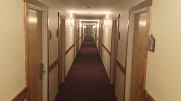 A hotel hallway with wooden doors, carpeted floors, and wall-mounted light fixtures.
