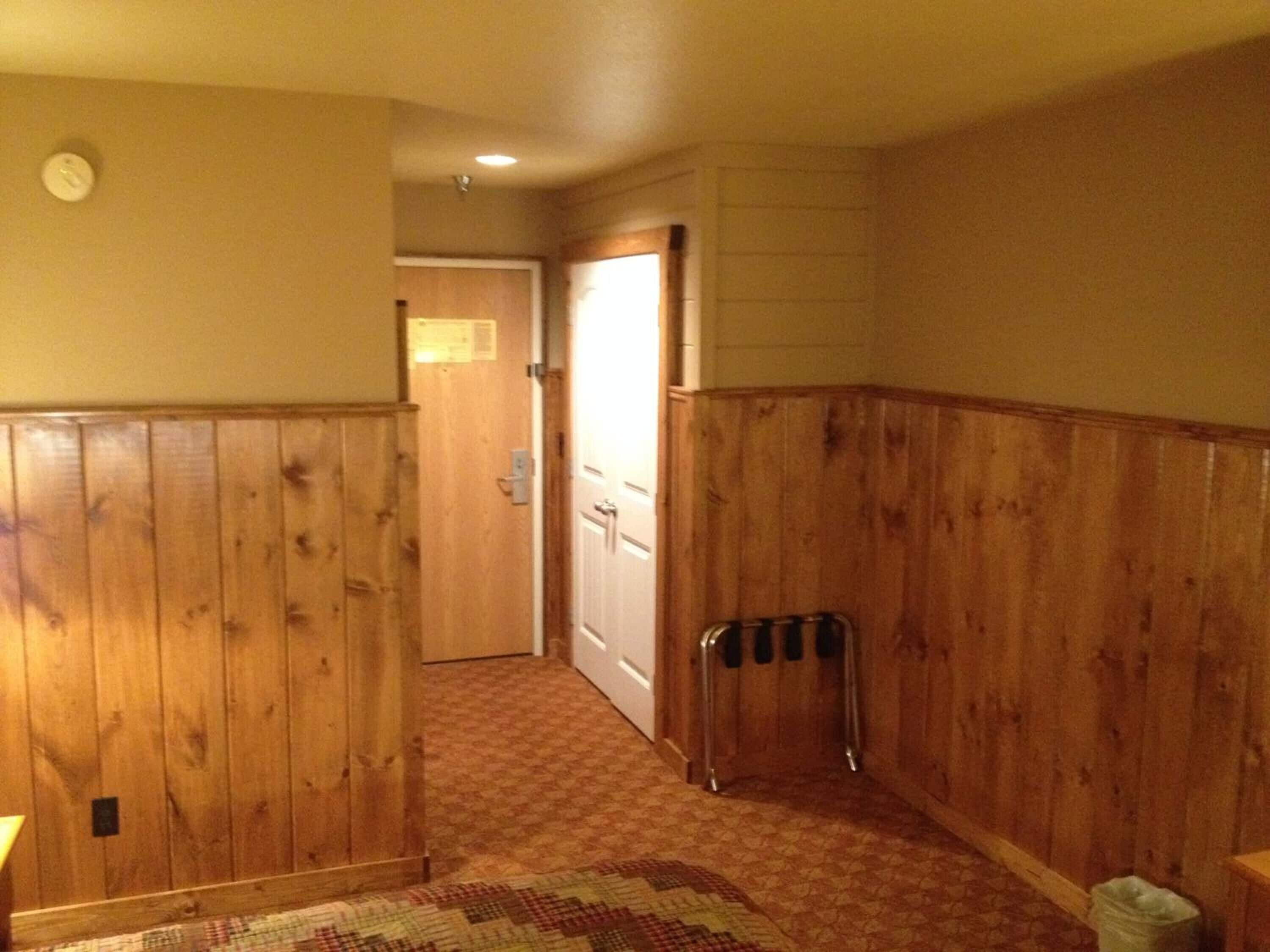 Un couloir avec des lambris en bois, un radiateur et un tapis à motifs.