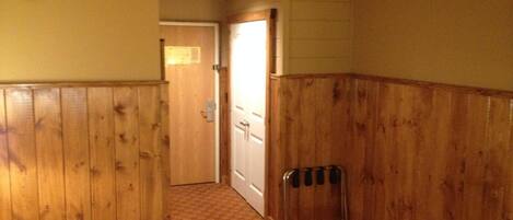 A hallway with wooden paneling, a radiator, and a patterned rug.