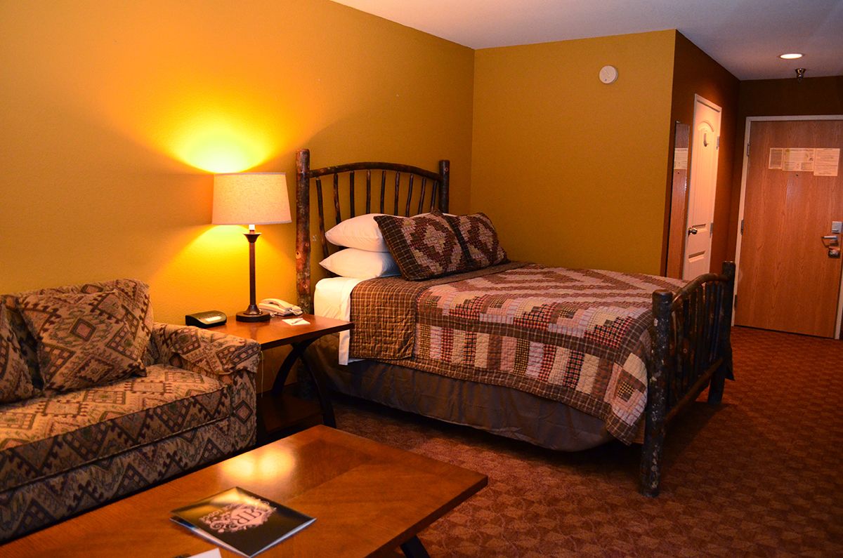 Une chambre d’hôtel avec un lit, un canapé, une table et une lampe.