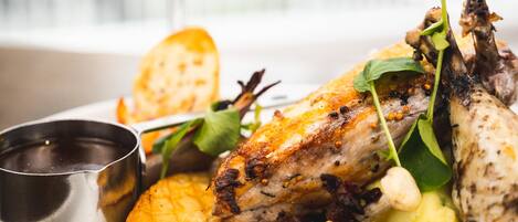 A plate of food with a glass of white wine and a metal cup on a table.