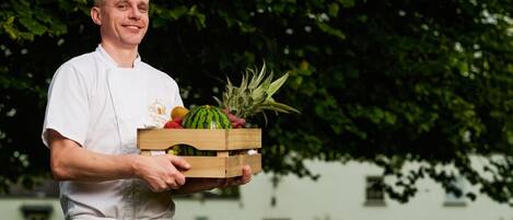 A person holding a wooden crate with various fruits and vegetables.