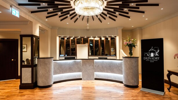 A hotel lobby with a modern chandelier, a reception desk, and a wooden floor. - Dunadry Hotel and Gardens (Antrim)