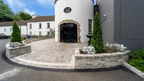 A building with a round tower, a black door, and stone steps leading to the entrance. - Dunadry Hotel and Gardens (Antrim)