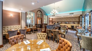 A spacious hotel lobby with a high ceiling, a chandelier, and a bar area. - Dunadry Hotel and Gardens (Antrim)