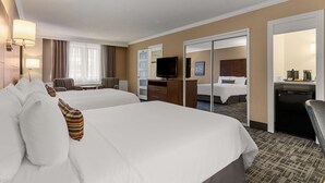Una habitación de hotel con dos camas, televisión, escritorio y un minibar.