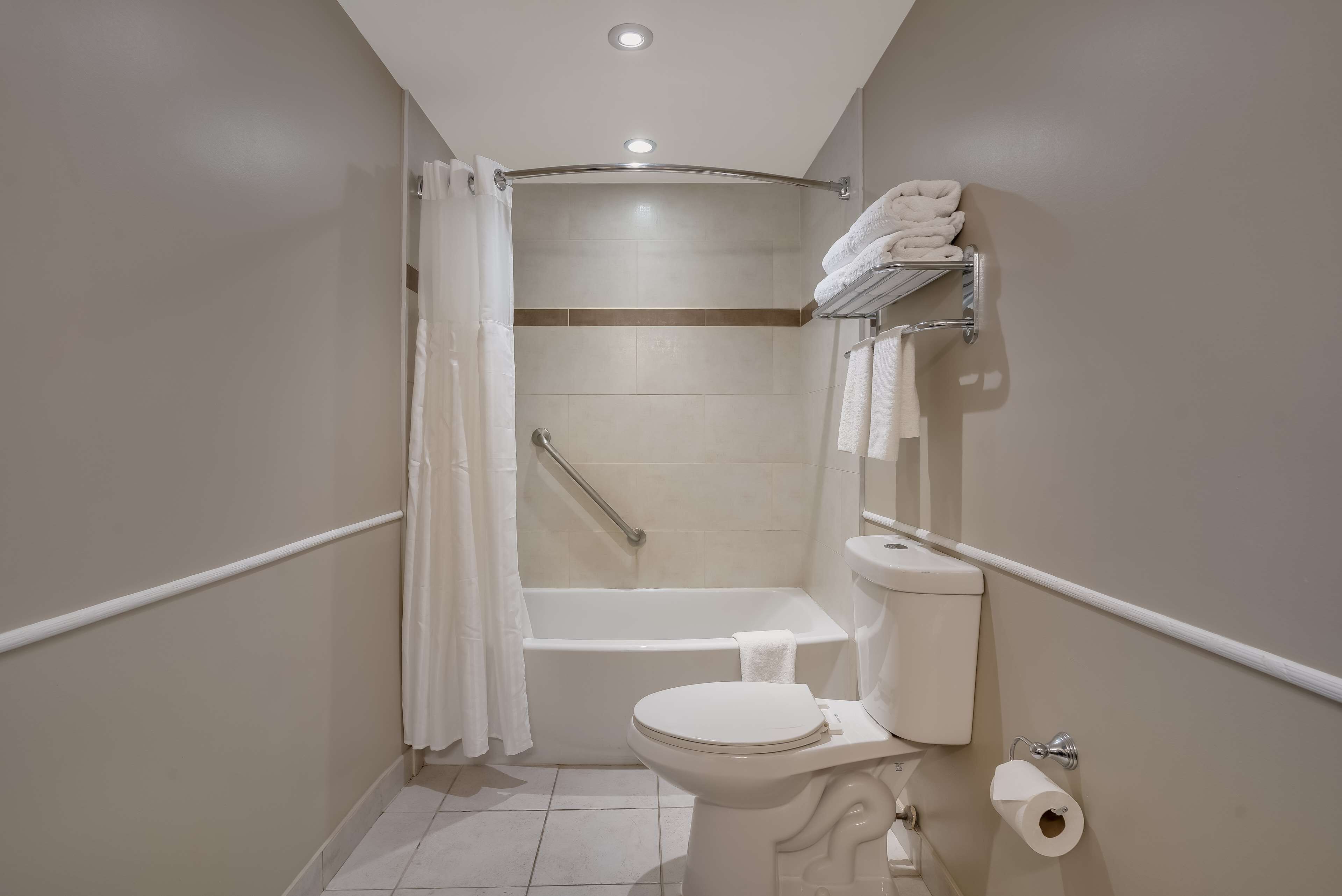 Une petite salle de bain moderne, équipée de toilettes, d’une douche avec une porte en verre et d’un porte-serviettes.