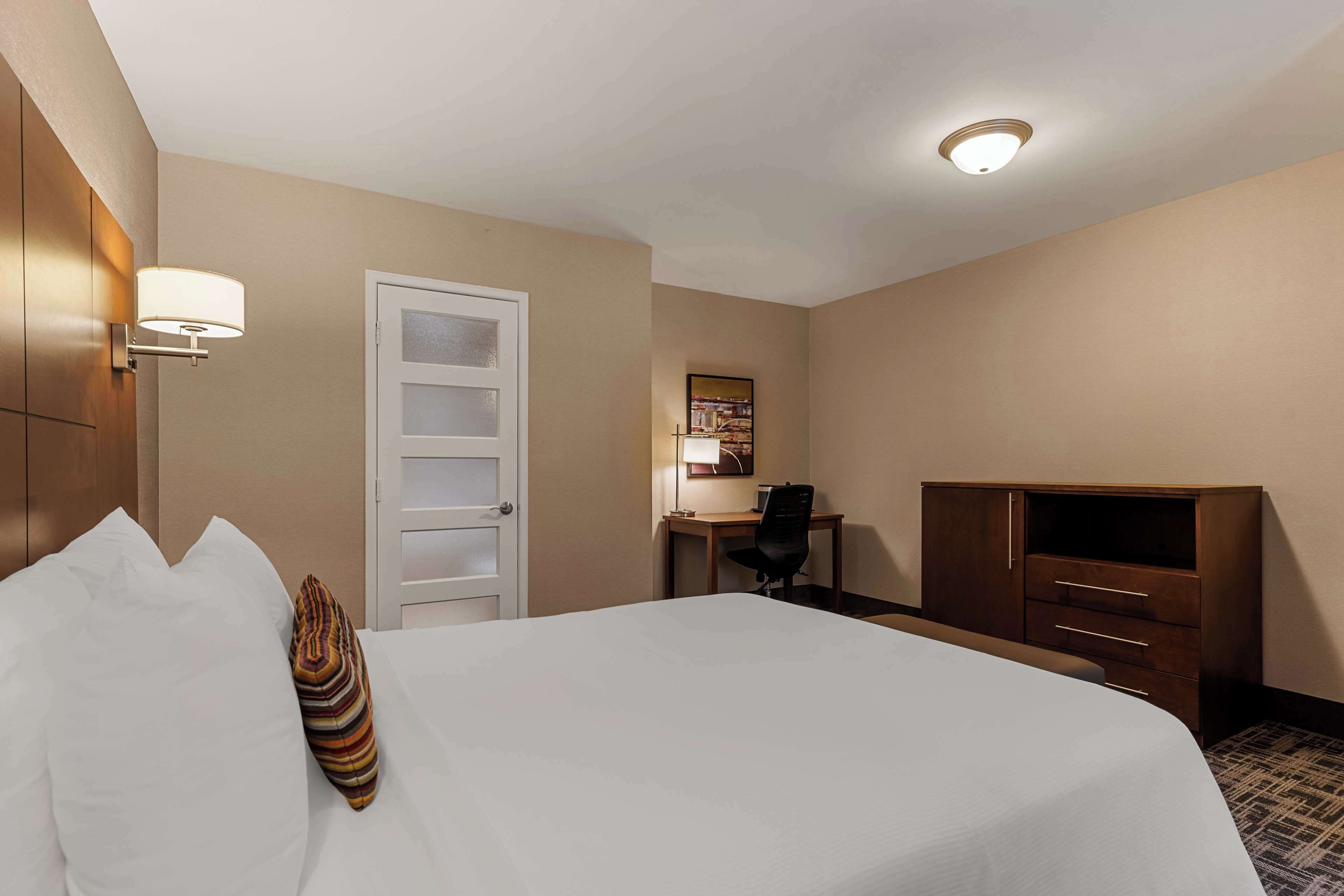 Een hotelkamer met een bed, een bureau, een stoel, een televisie en een kledingkast.