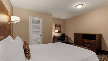 Een hotelkamer met een bed, een bureau, een stoel, een televisie en een kledingkast.