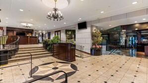 Un vestíbulo amplio con una escalera central, un candelabro y un diseño decorativo en el suelo.