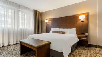 A hotel room with a large bed, a bedside table, a lamp, and a patterned carpet.