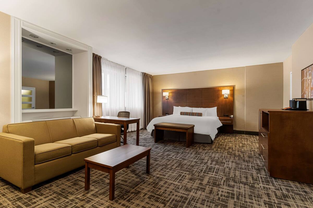 Una habitación de hotel con cama, sofá, escritorio y una mesita.