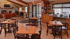 A restaurant with wooden tables and chairs, a fireplace, and a bar area. - AmericInn by Wyndham St. Cloud MN I-94 (St Cloud)