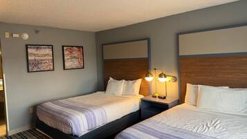 Habitación de hotel con dos camas, una mesita de noche con lámpara y una obra de arte en la pared.
