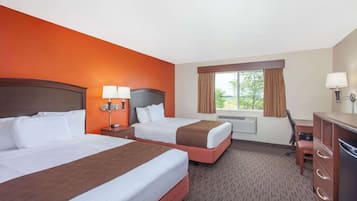 A hotel room with two beds, a desk, a chair, and a dresser.