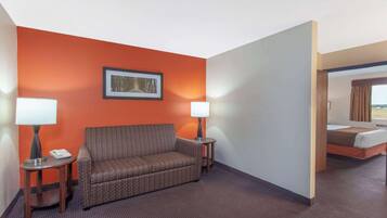 Habitación de hotel con un sofá estampado, dos mesitas de noche con lámparas, un cuadro en la pared y una cama con vistas.