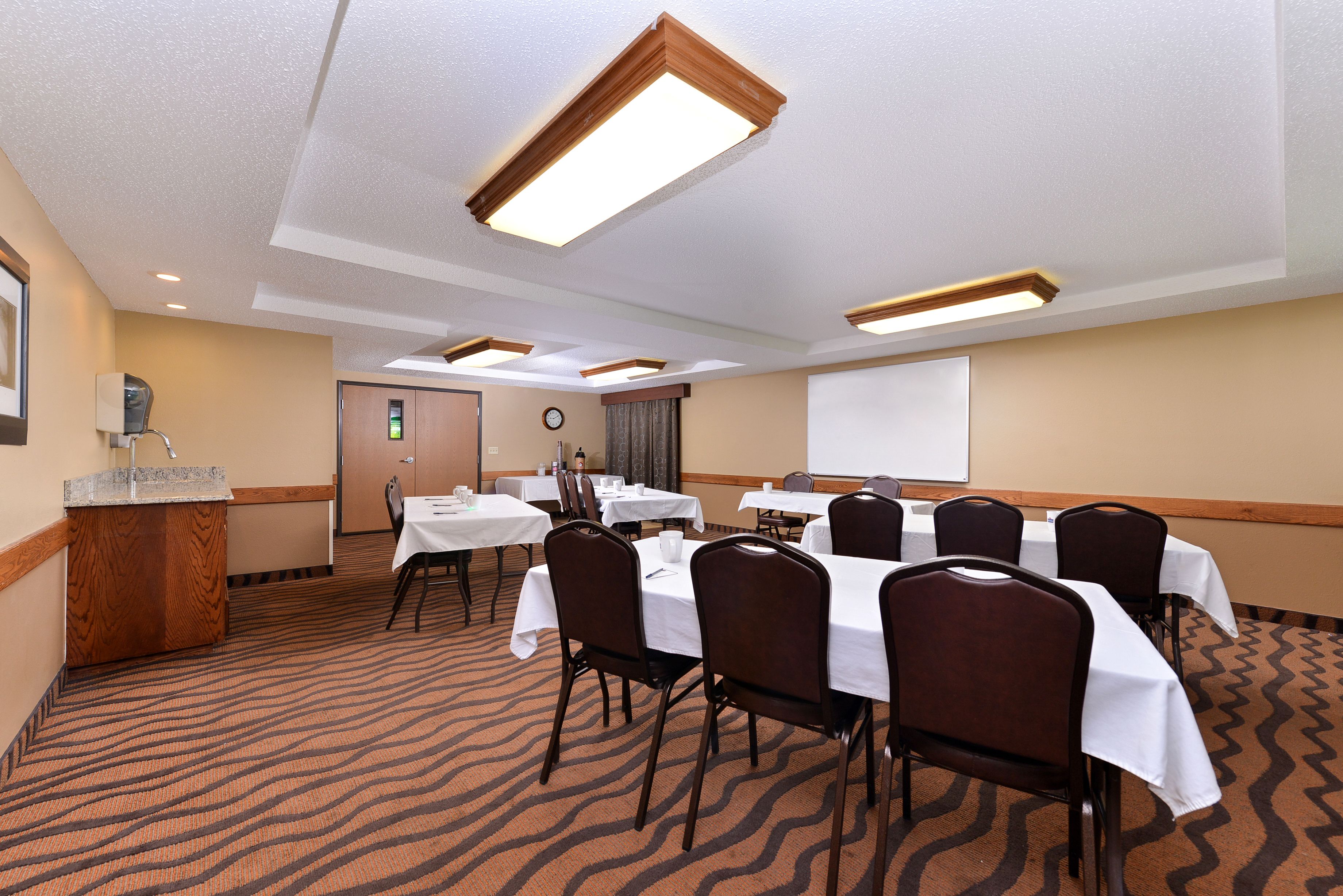 A conference room with tables and chairs, a podium, and a projector screen.