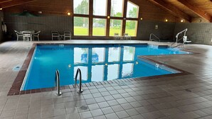 An indoor swimming pool with clear views through large windows, tiled flooring, and a wooden ceiling. - AmericInn by Wyndham St. Cloud MN I-94 (St Cloud)