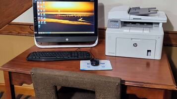 Un escritorio de madera con una laptop HP, una impresora, un teclado y un ratón.
