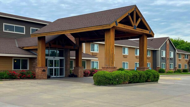 A hotel entrance with a covered waiting area, brick facade, and a parking lot. - Quality Inn Atchison (Atchison)