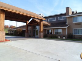 A two-story building with a covered entrance, large windows, and a brick facade.