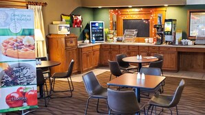 A breakfast area with tables, chairs, a coffee machine, and a refrigerator. - Quality Inn Atchison (Atchison)