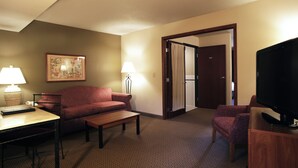 Una habitación de hotel con sofá, una mesita, un televisor y dos lámparas.