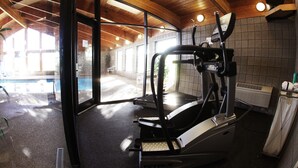 Un gimnasio con equipamiento de ejercicio, una piscina y vistas al exterior.