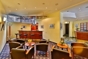 Una hall d'albergo con zona bar, sedute e reception.