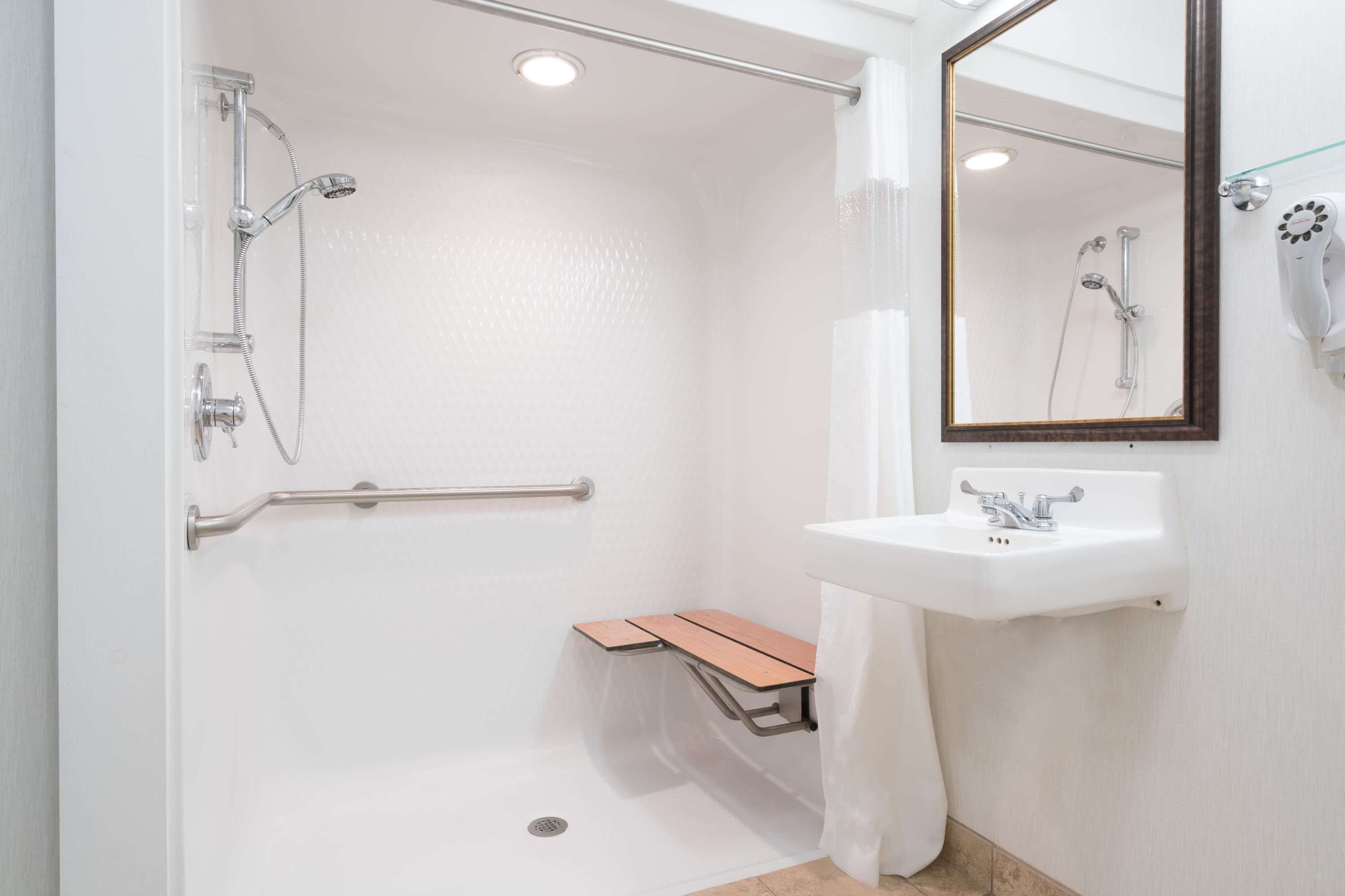 A modern bathroom with a shower, a sink, a mirror, and a towel rack.
