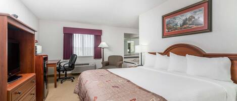 A hotel room with a bed, a desk, a chair, a television, and a framed picture on the wall.