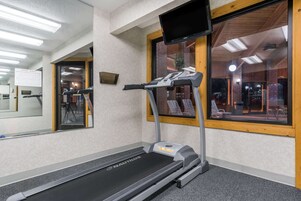 Una cinta de correr Nautilus en una habitación de hotel, con un espejo grande, marco de ventana de madera y vistas al interior del hotel.