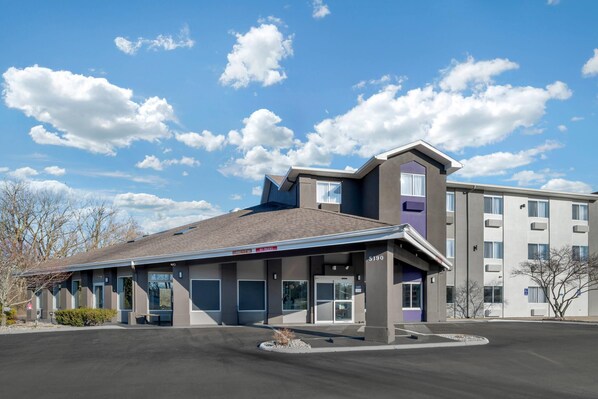 A modern hotel with a covered entrance, multiple rooms, and a parking lot.
