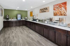 A breakfast area with a counter, coffee machines, and food dispensers.