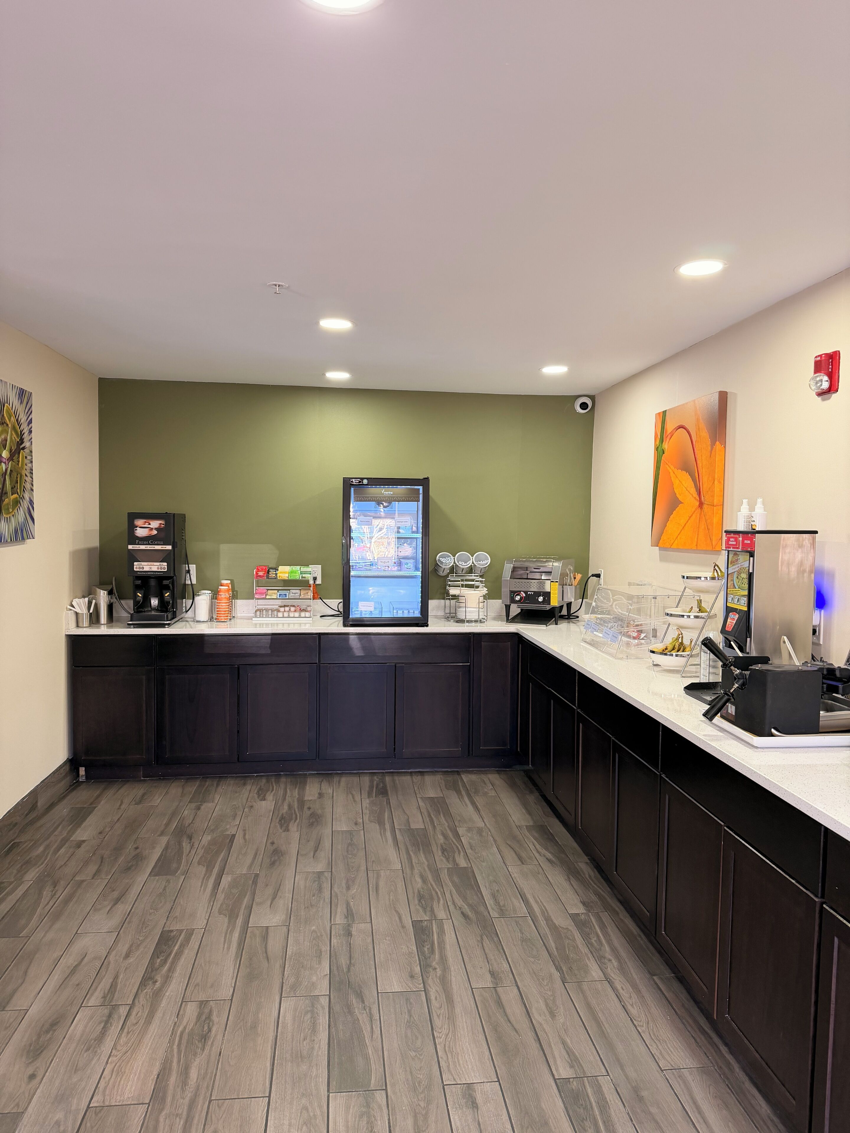 A modern kitchen with a coffee machine, a digital screen, and a refrigerator.