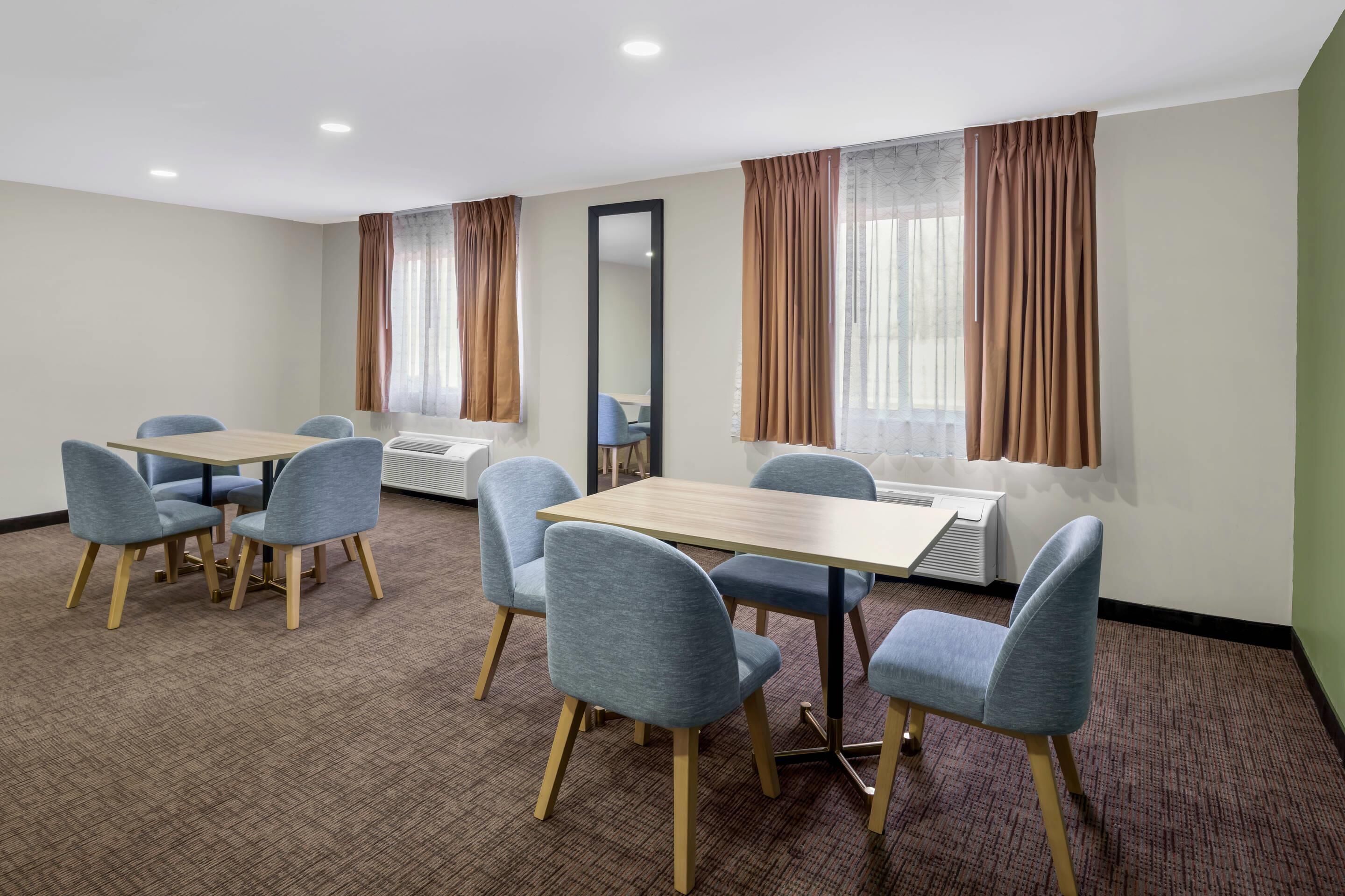 A conference room with a long table, six chairs, a large mirror, and two air conditioning units.