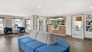 A reception area with a blue sofa, wooden flooring, and a reception desk.