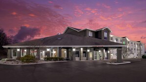A hotel with a covered entrance, multiple windows, and a parking lot.