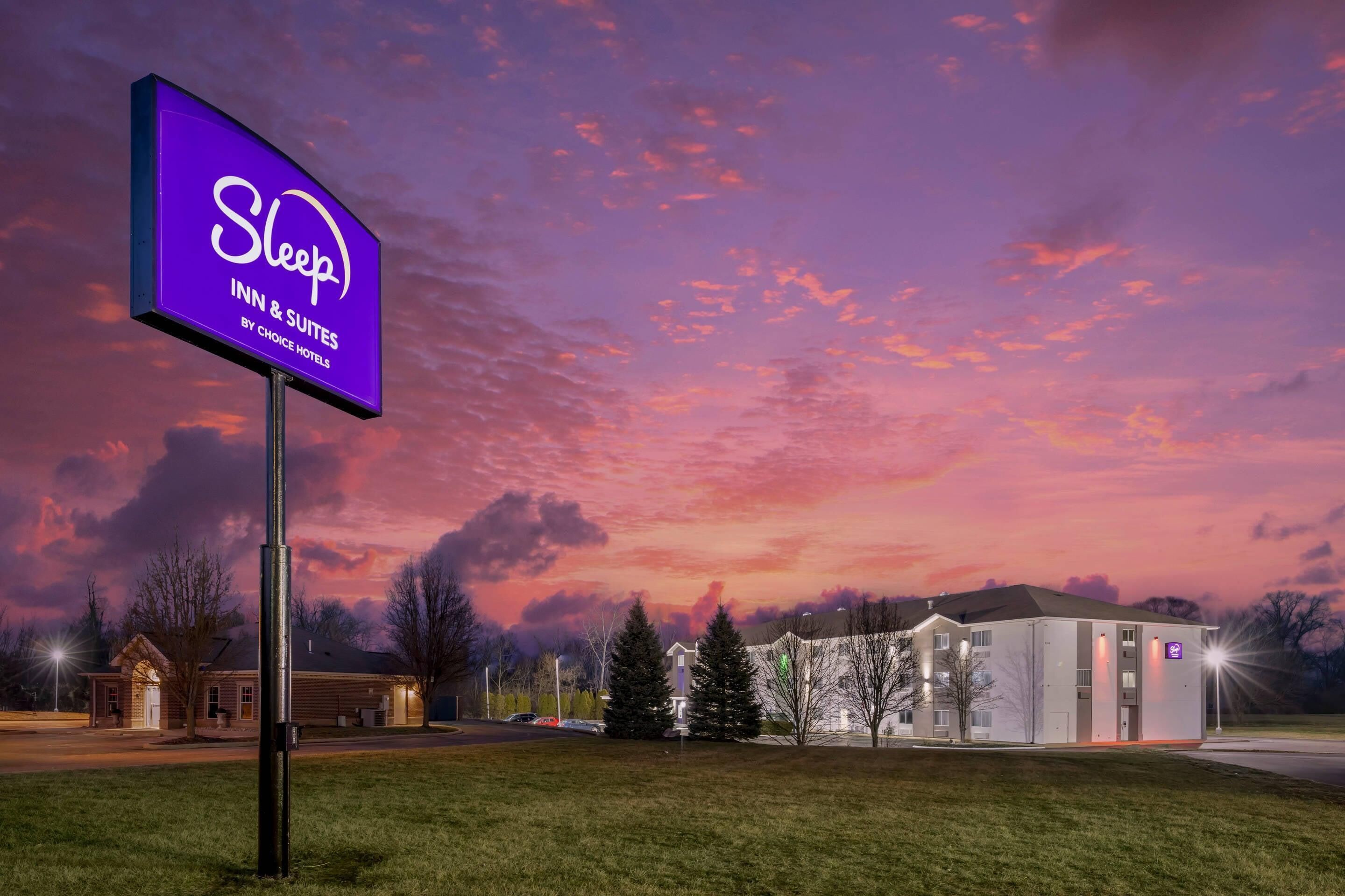 A Sleep Inn & Suites sign, a building with a flat roof, and a parking lot.