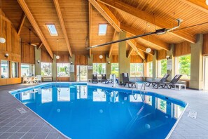 An indoor swimming pool with wooden beams, lounge chairs, and a view of the outdoors. - Comfort Inn Norwalk - Sandusky (Norwalk)