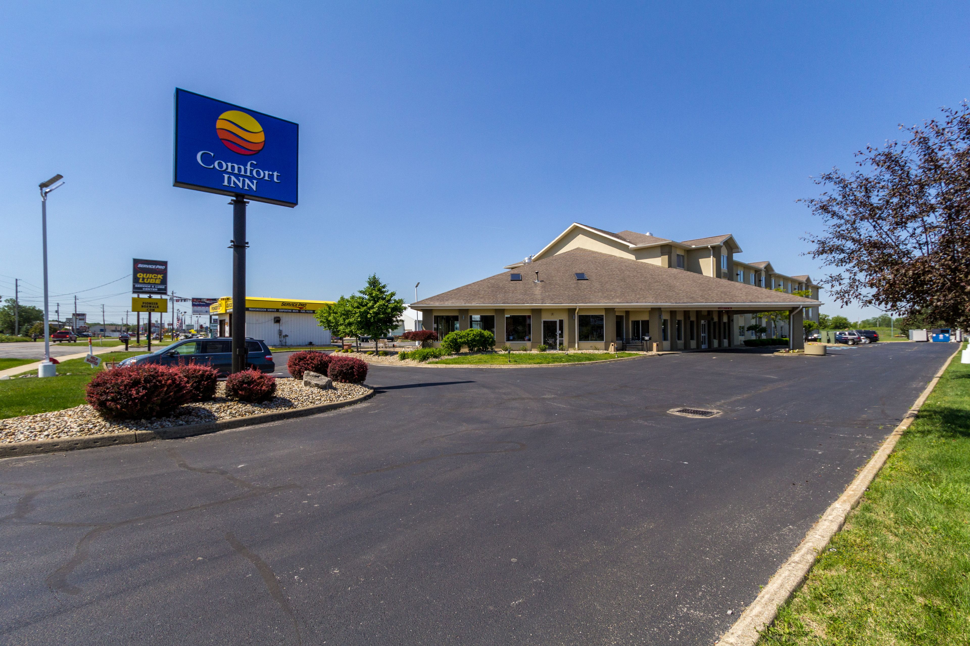 A Comfort Inn hotel with a large sign, a parking lot, and a building with a beige roof.