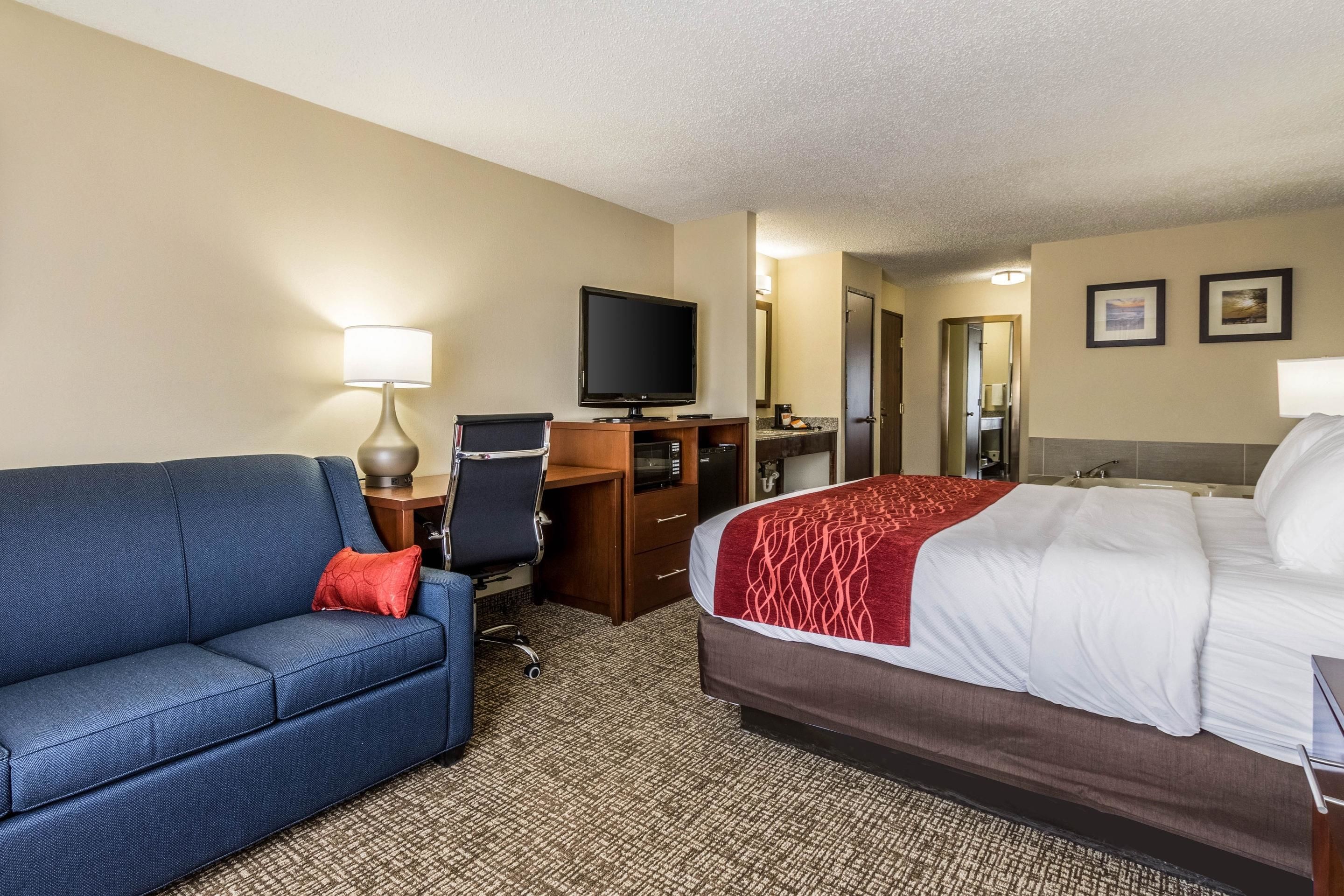 Une chambre d’hôtel comprenant un lit, un bureau avec un ordinateur, une chaise, une télévision et un canapé.