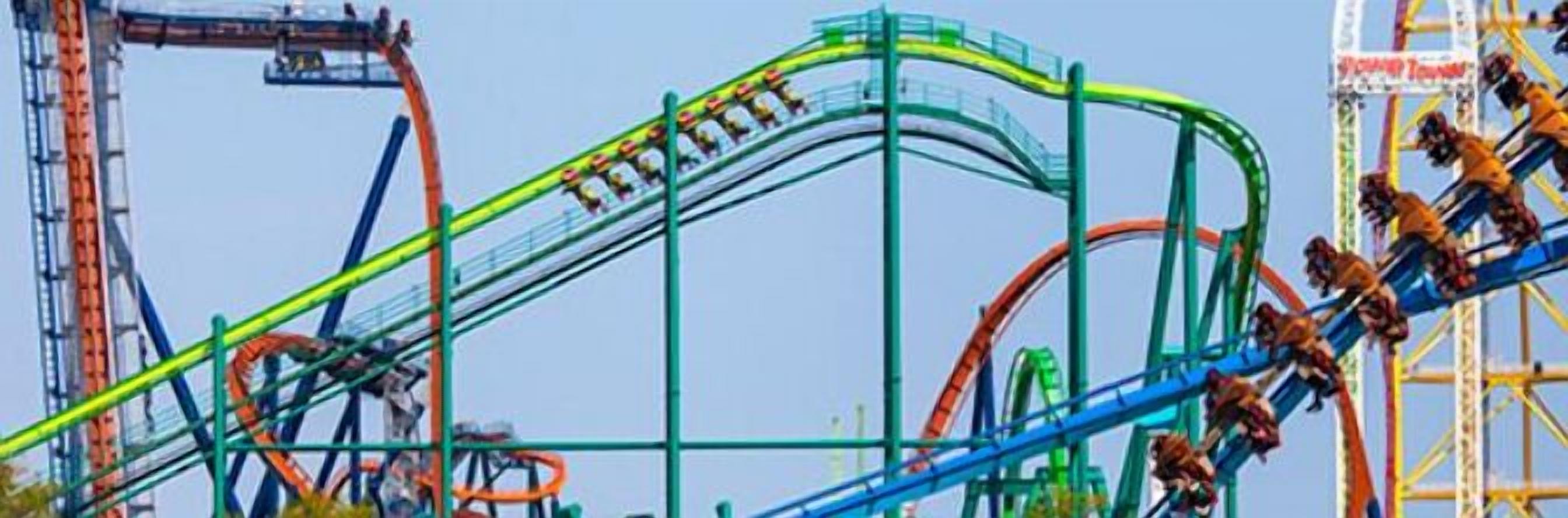 A roller coaster with a green track and a blue track, surrounded by other amusement park rides.