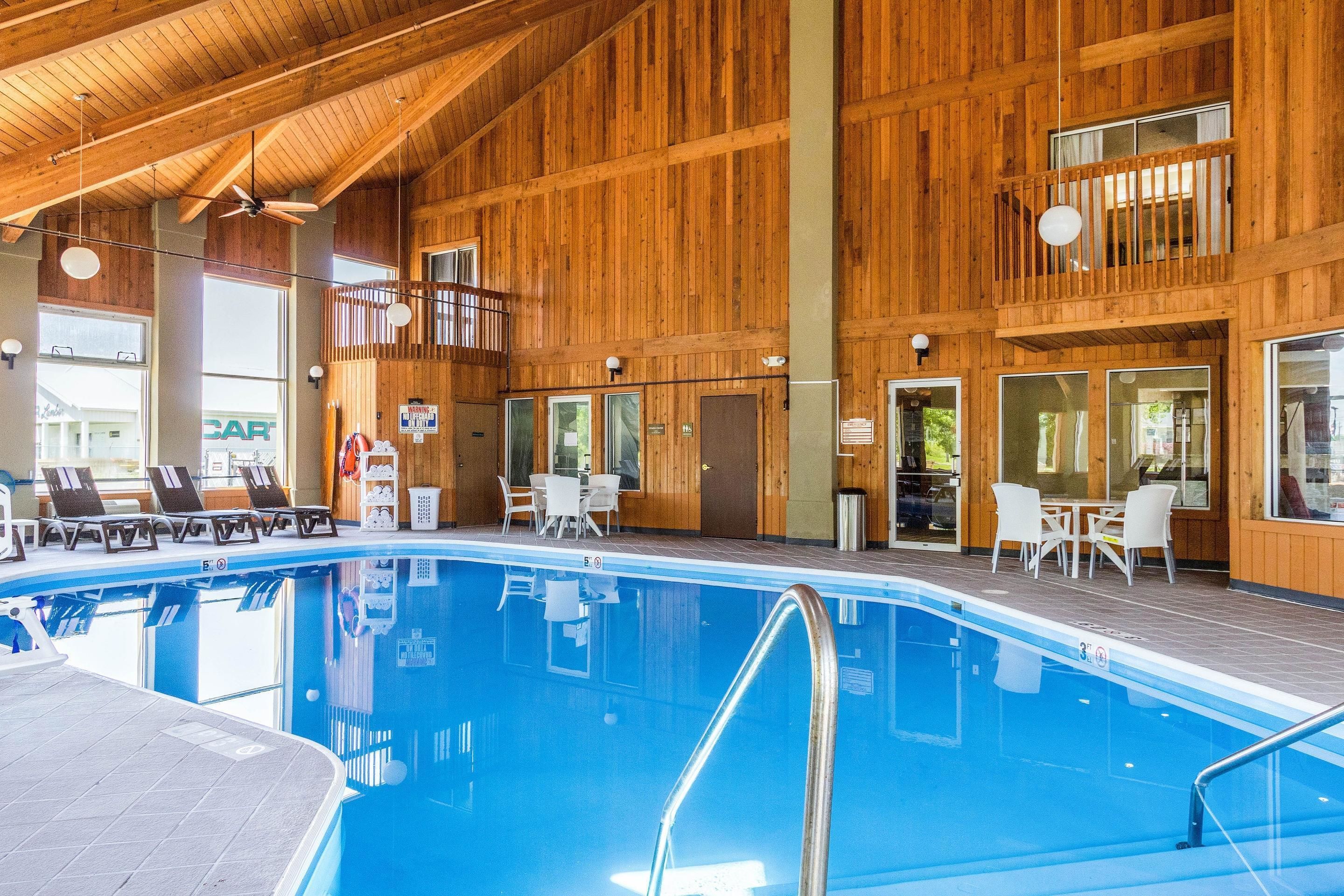 Una piscina interior con paredes de madera y un balcón con vistas a la piscina.