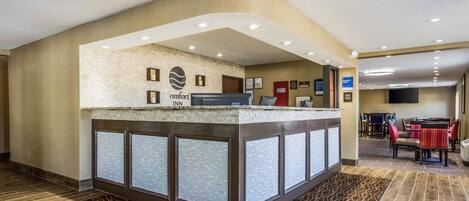 Un área de recepción con mostrador, cuadros enmarcados y un cartel que dice "Comfort Inn".